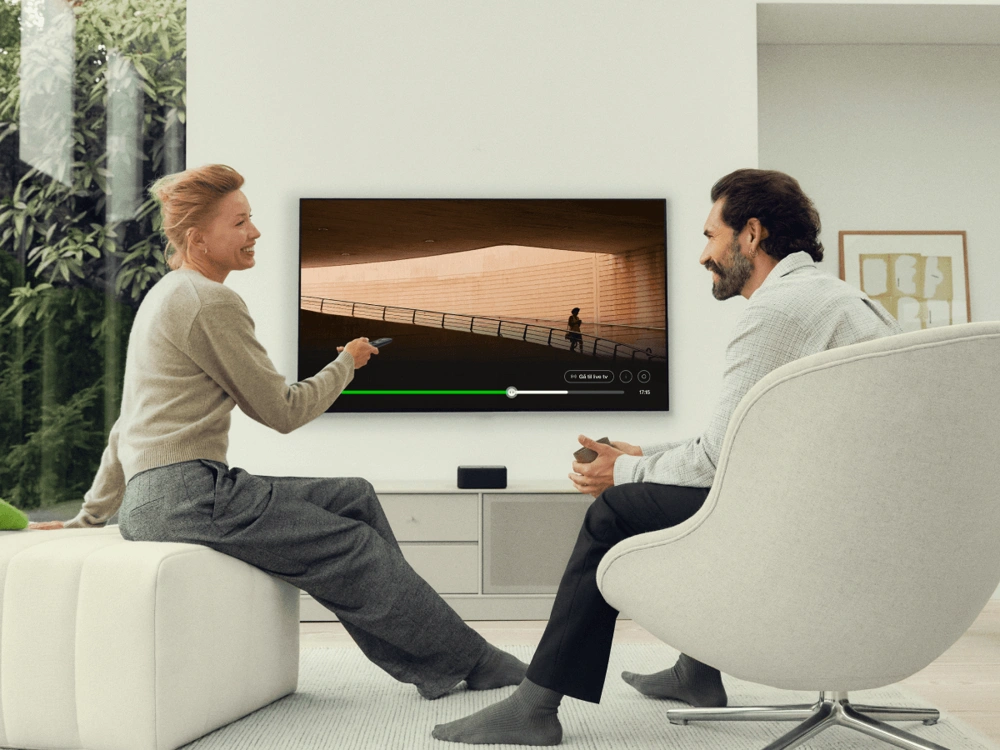 Person slapper af i moderne stue med tv og lounge-stol i lyst og minimalistisk hjemmemiljø.