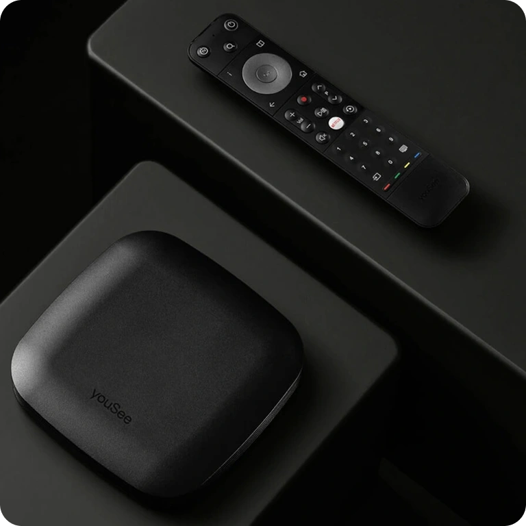 YouSee tv-boks og fjernbetjening placeret på mørk overflade i stilrent produktfoto.