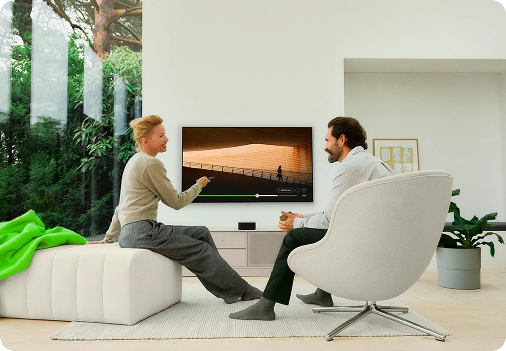 Person slapper af i moderne stue med tv og lounge-stol i lyst og minimalistisk hjemmemiljø.