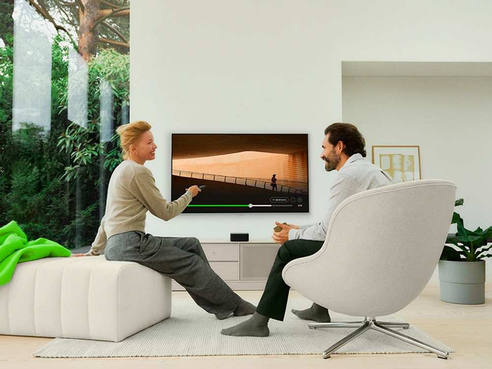 Person slapper af i moderne stue med tv og lounge-stol i lyst og minimalistisk hjemmemiljø.
